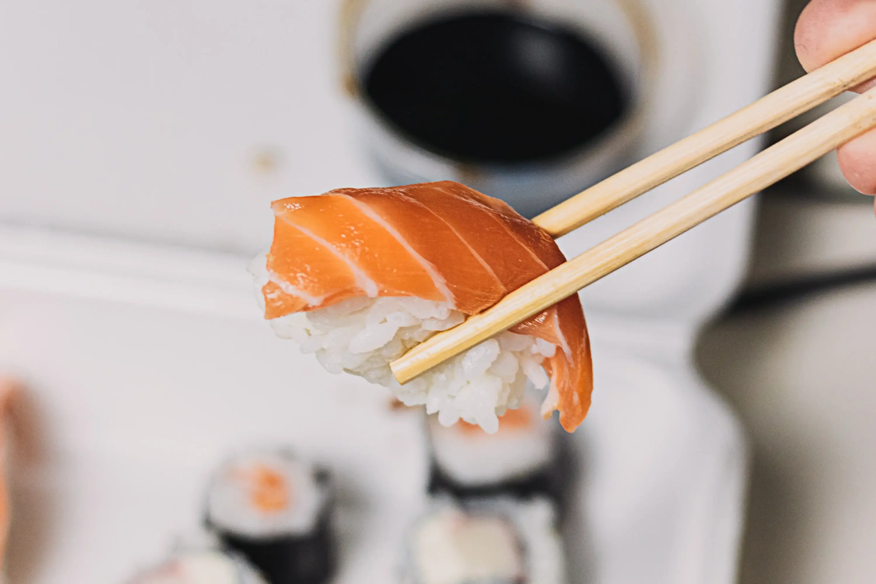 salmon sushi held with chopsticks